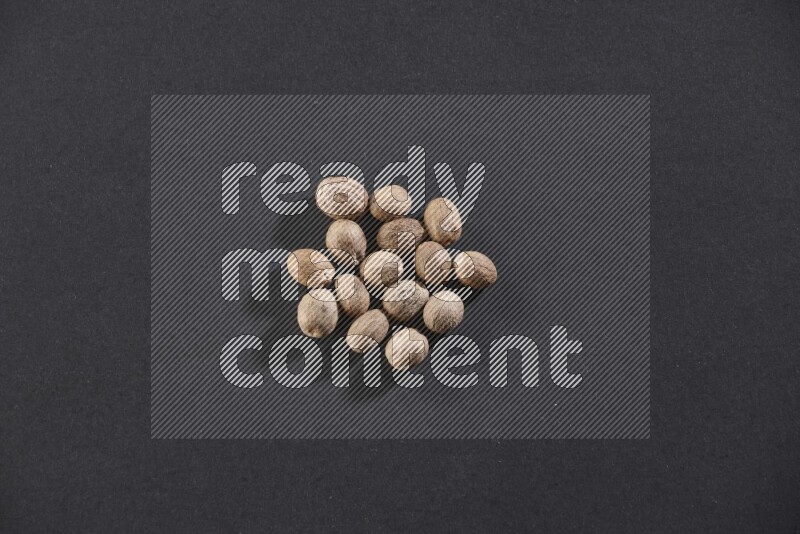 A bunch of whole nutmeg seeds on a black flooring