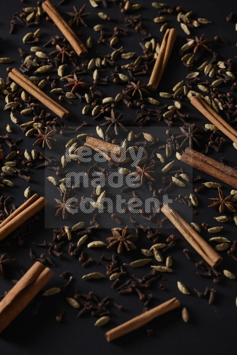 Cinnamon Sticks, Star anise, Cardamom and cloves on a black background