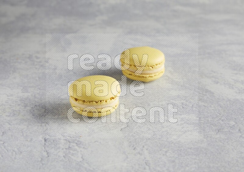 45º Shot of two Yellow Lime macarons  on white  marble background