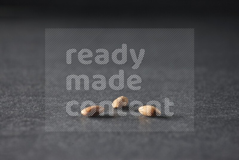 3 peeled almonds on a black background in different angles