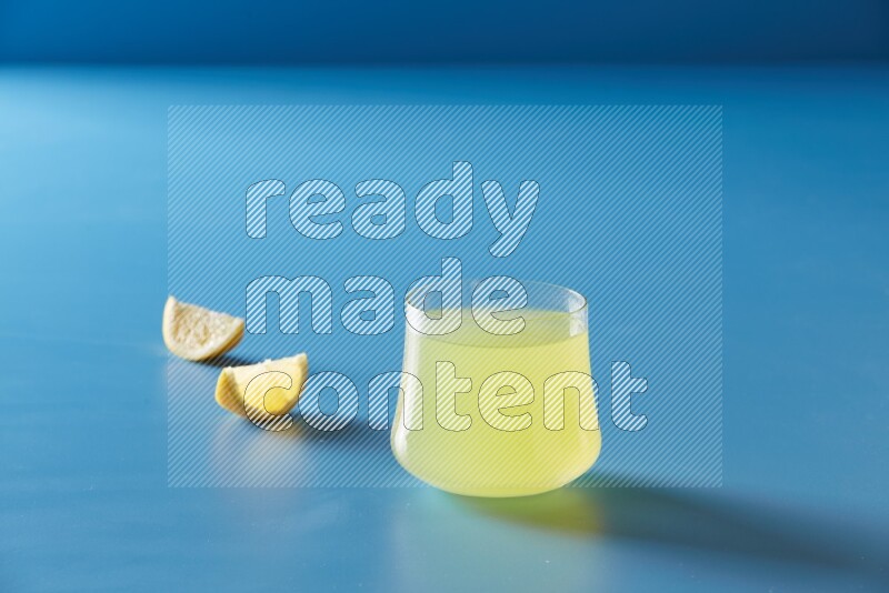 glass of lemon juice on blue background