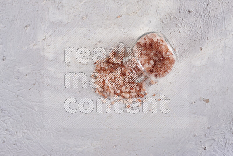 A glass jar full of coarse himalayan salt crystals on white background