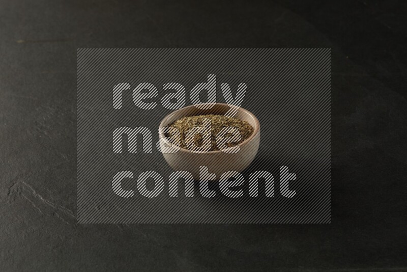 multi color round sauce bowl filled with herbs on grey textured countertop