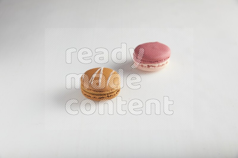 45º Shot of of two assorted Brown Irish Cream, and Pink Litchi Raspberry macarons on white background