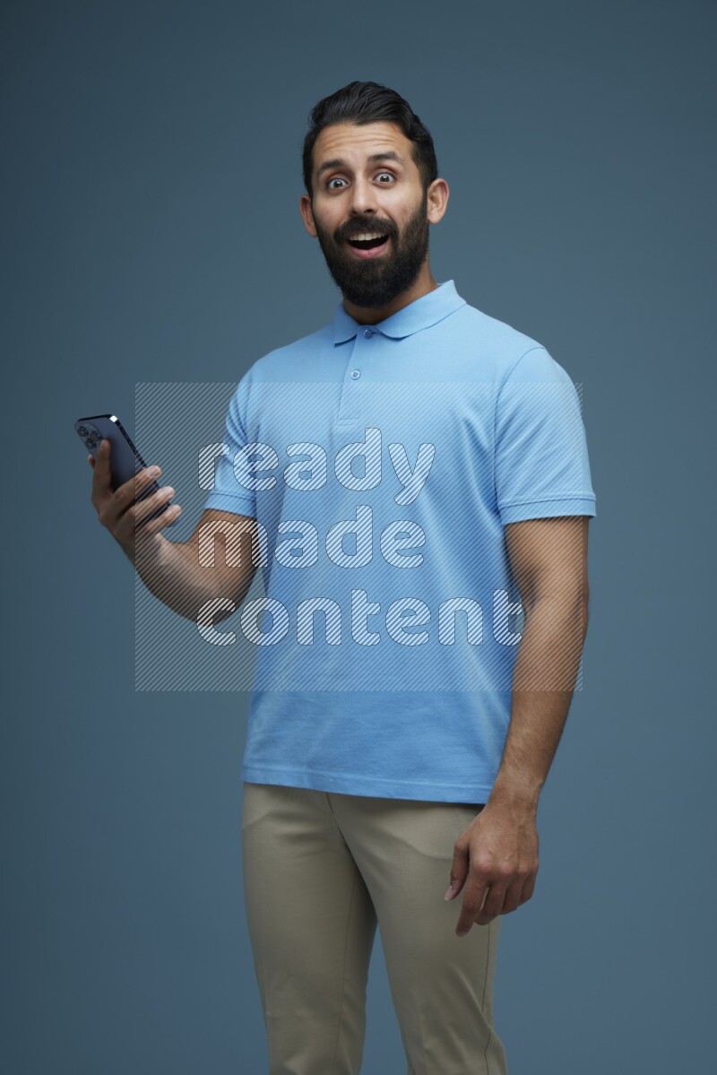 Man posing with a phone in a blue background wearing a Blue shirt