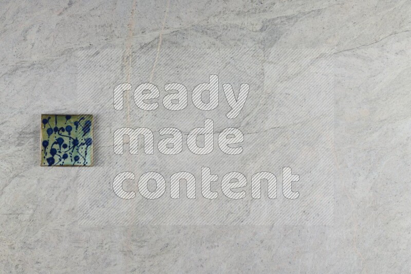 A decorative pottery coaster on grey marble background