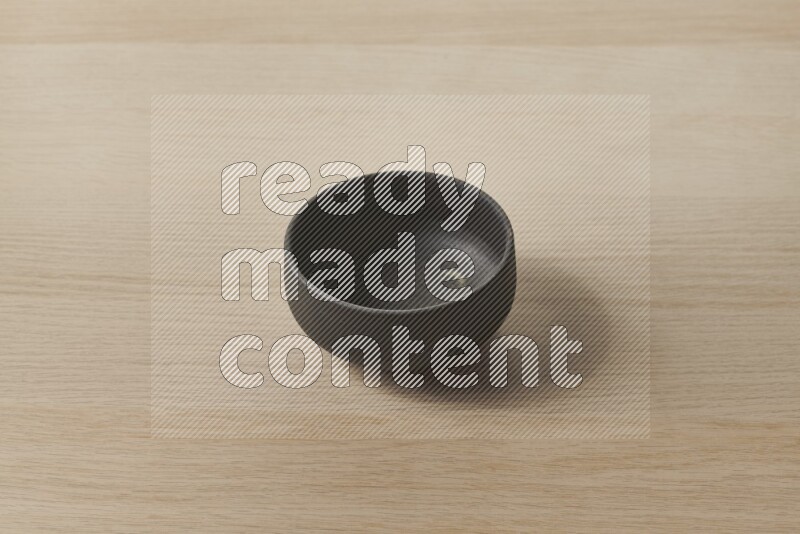 A black pottery bowl on light wooden background