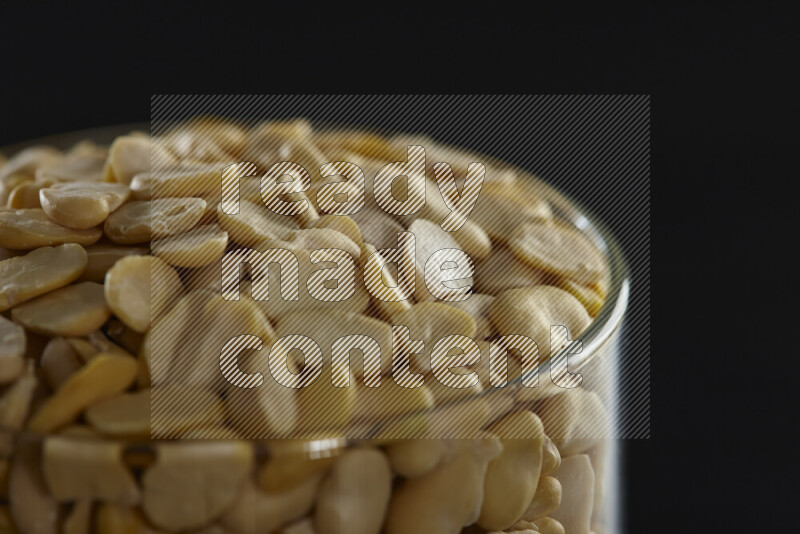 Crushed beans in a glass jar on black background