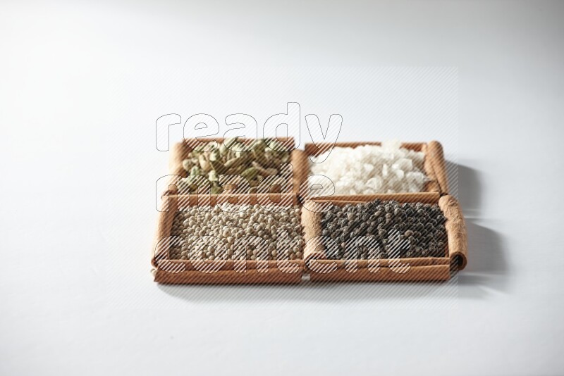 4 squares of cinnamon sticks full of cardamom, salt, white pepper and black pepper on white flooring