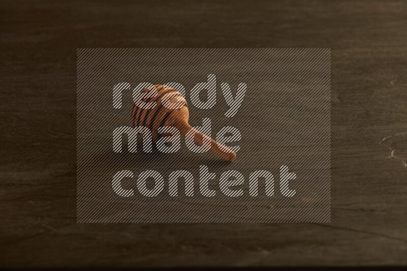 Wooden honey dipper on black slate background