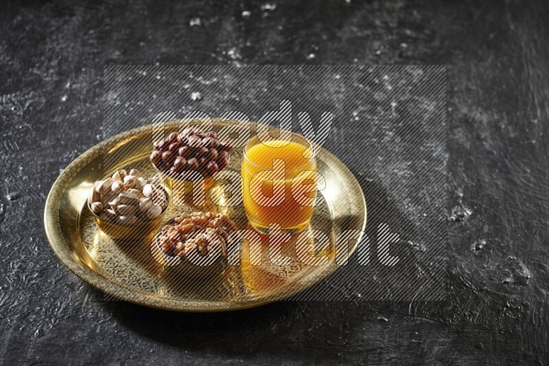 Nuts in metal bowls with qamar eldin on a tray in dark setup