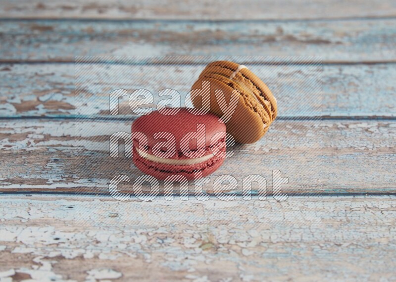 45º Shot of of two assorted Brown Irish Cream, and Red Velvet macarons on light blue background