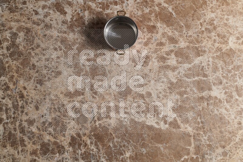 A small copper pot on beige marble background