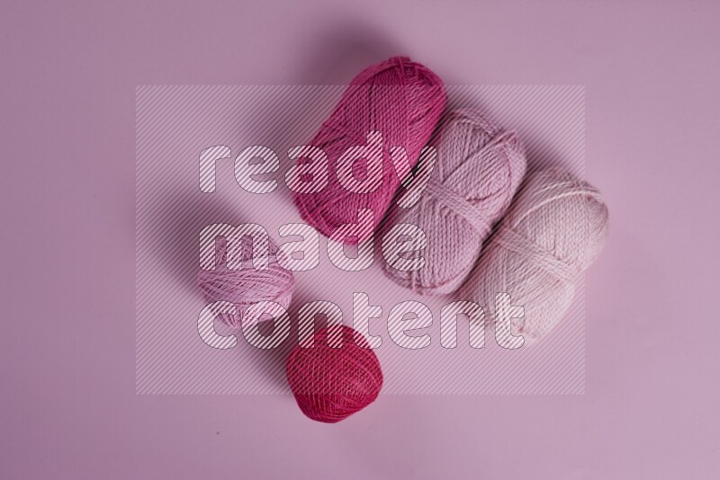 A pink collection of sewing and tailoring tools arranged on a pink background