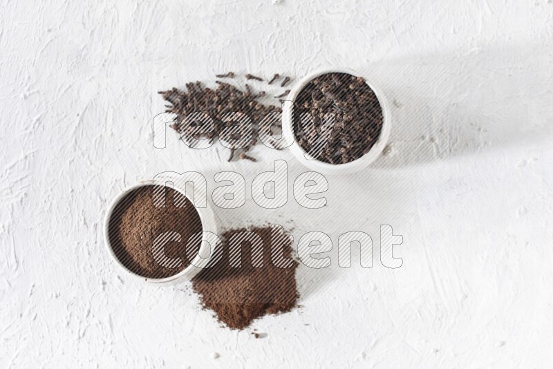 وعاءين من السيراميك بيج اللون، أحدهما مملوء بالقرنفل والآخر مملوء بالبودرة على أرضية بيضاء