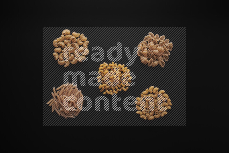 Different pasta types in bunches on black background