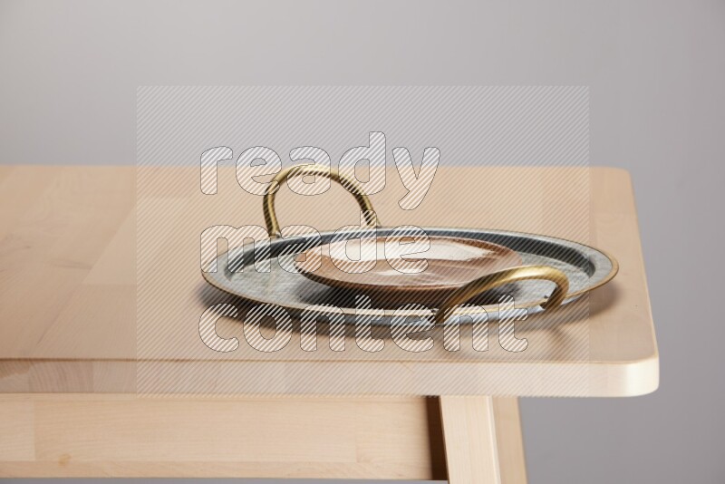 multicolored plate placed on a rounded stainless steel tray with golden handels on the edge of wooden table