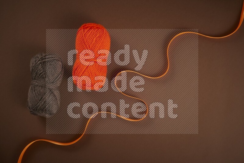 An orange collection of sewing and tailoring tools arranged on a brown background
