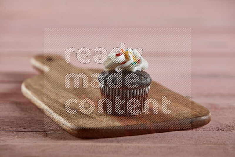 Chocolate mini cupcake topped with cream on a wooden board