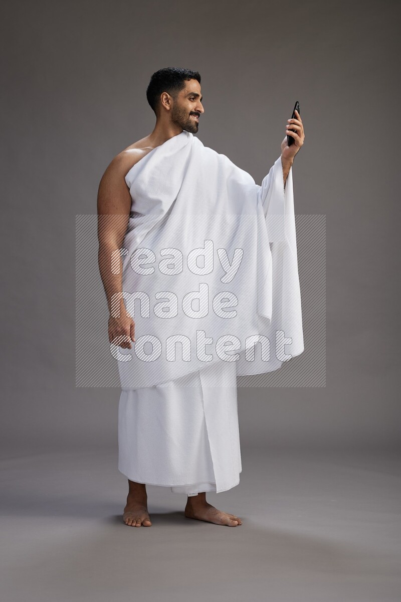 A man wearing Ehram Standing taking selfie on gray background