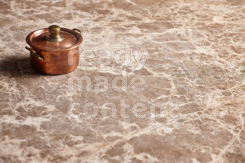 A small copper pot on beige marble background