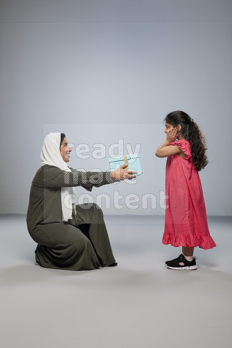 A girl giving a gift to her mother on gray background