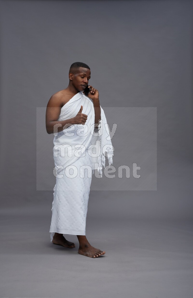 A man wearing Ehram Standing talking on phone on gray background
