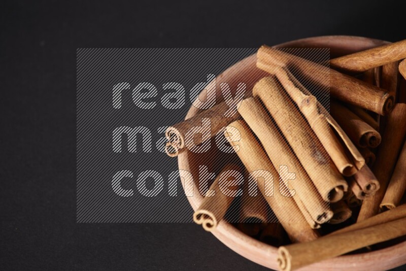 Cinnamon Sticks in a wooden bowl on black background