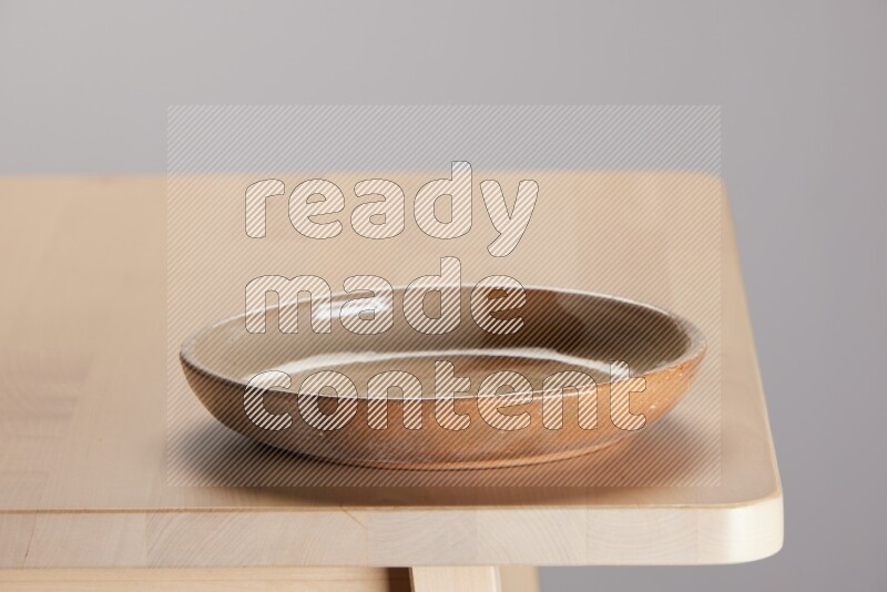 multi-colored pottery Plate on a wooden table edge