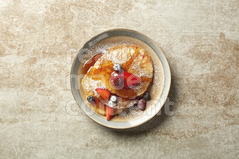 Three stacked mixed berries pancakes in a bicolor plate on beige background