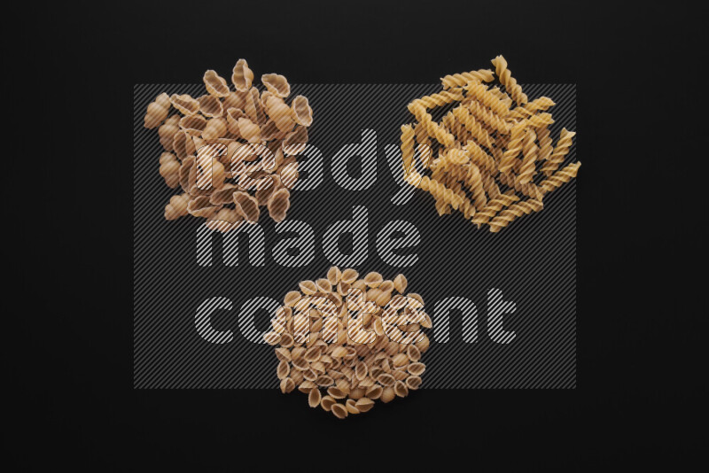 Different pasta types in bunches on black background