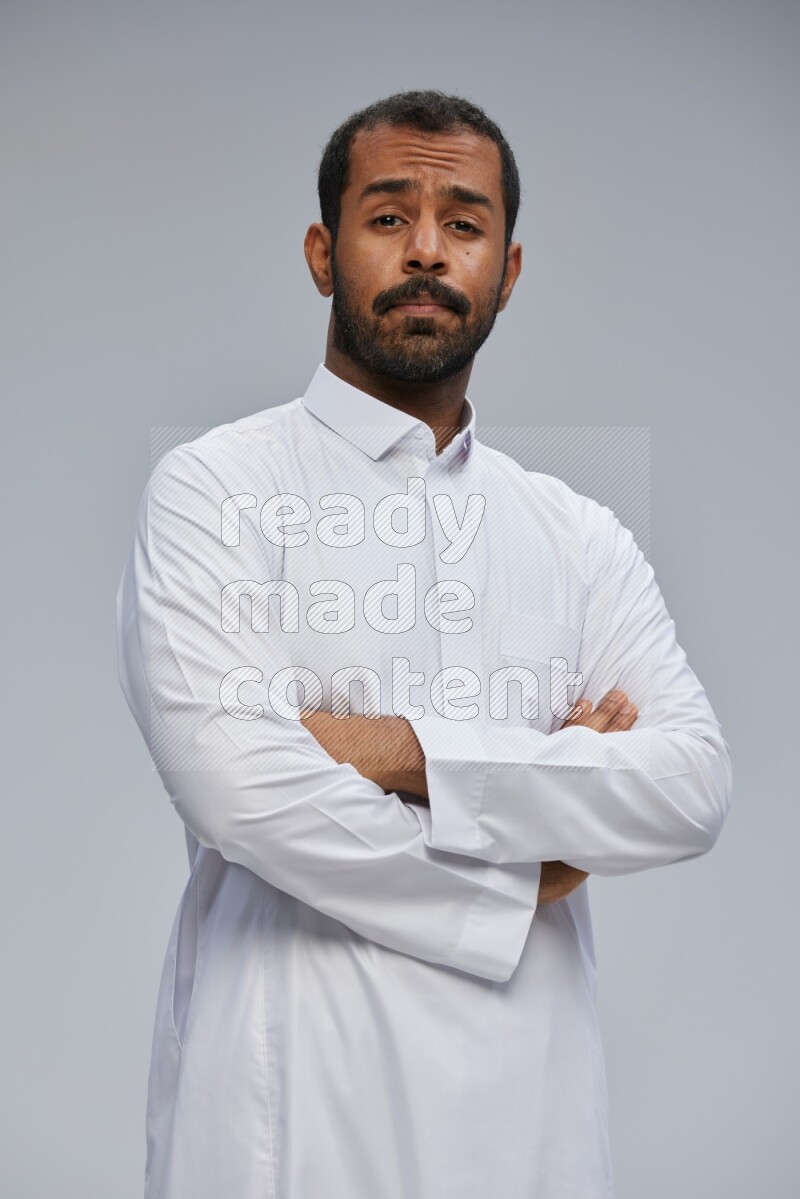 Saudi man wearing Thob standing with crossed arms on Gray background
