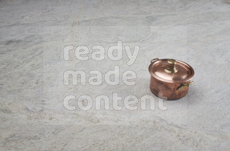A small copper pot on grey marble background
