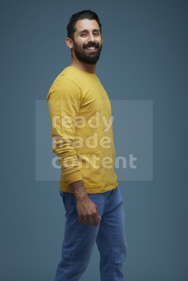 Man posing in a blue background wearing a yellow shirt