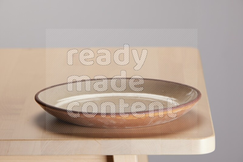 multi-colored pottery Plate on a wooden table edge