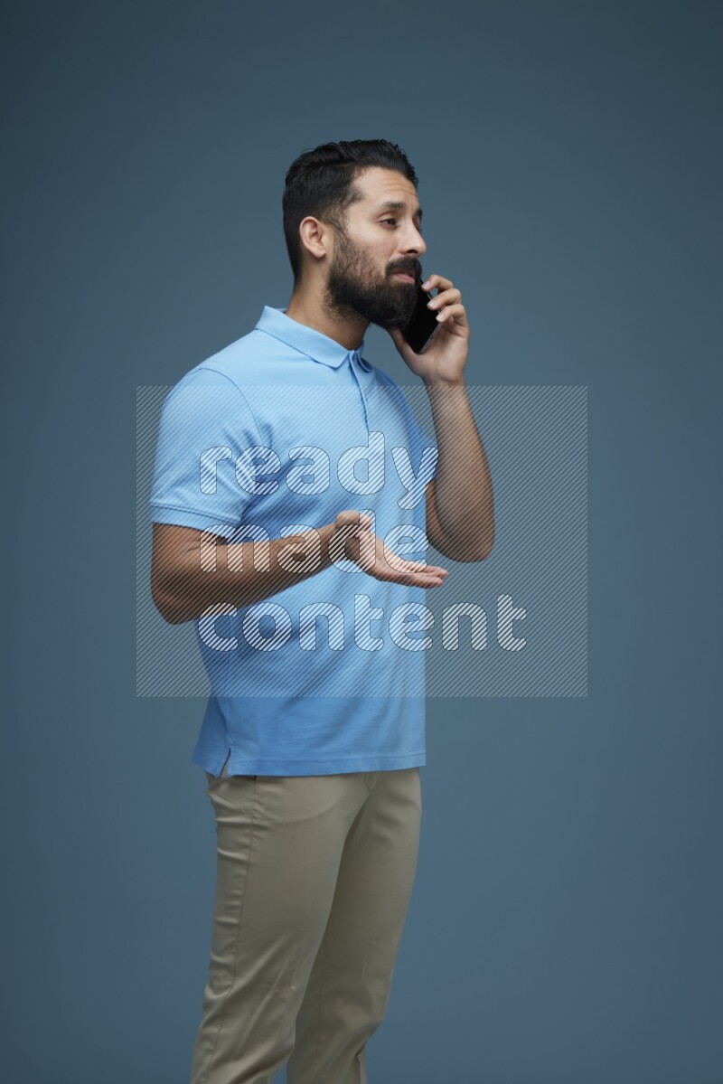 A man having a Call in a blue background wearing a Blue shirt