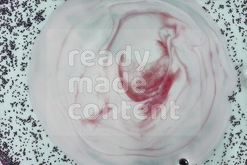 لقطة مقرّبة لدوامات من اللون الأحمر مع بريق أرجواني متلألئ منتشر على خلفية من اللون الأخضر