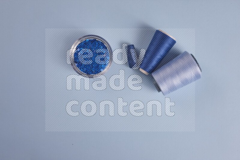 A blue collection of sewing and tailoring tools arranged on a blue background