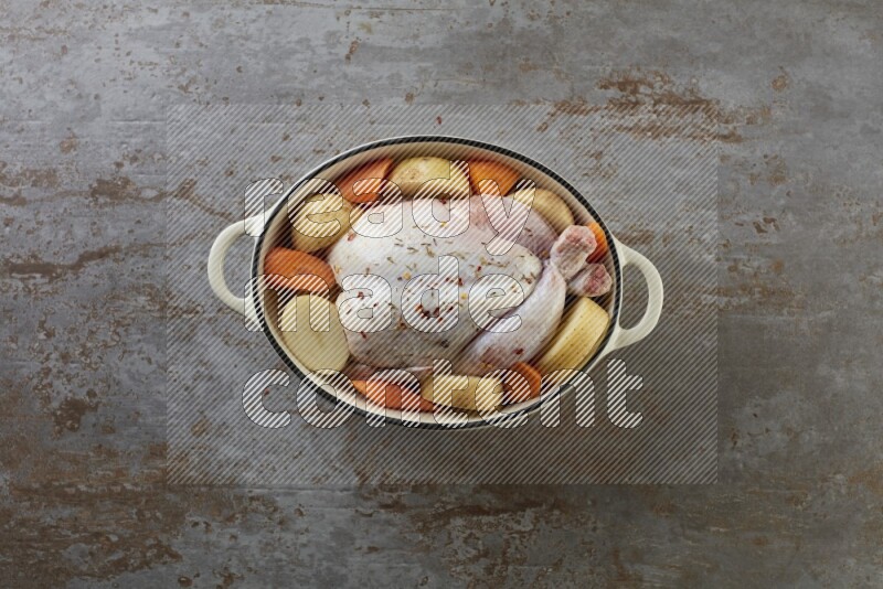 whole raw chicken on in a white ceramic pot direct on a rustic grey background