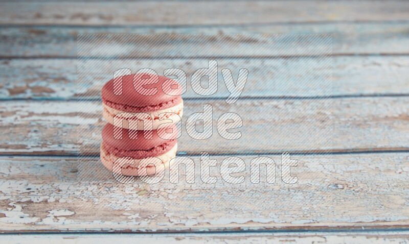 45º Shot of two Pink Litchi Raspberry macarons on light blue wooden background