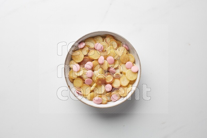 Top-view shot of pink chocolate chips cereal pancakes in a round bowl on white background