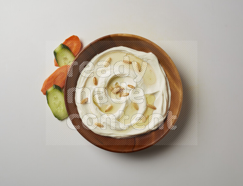 Lebnah garnished with pine nuts in a wooden plate on a white background