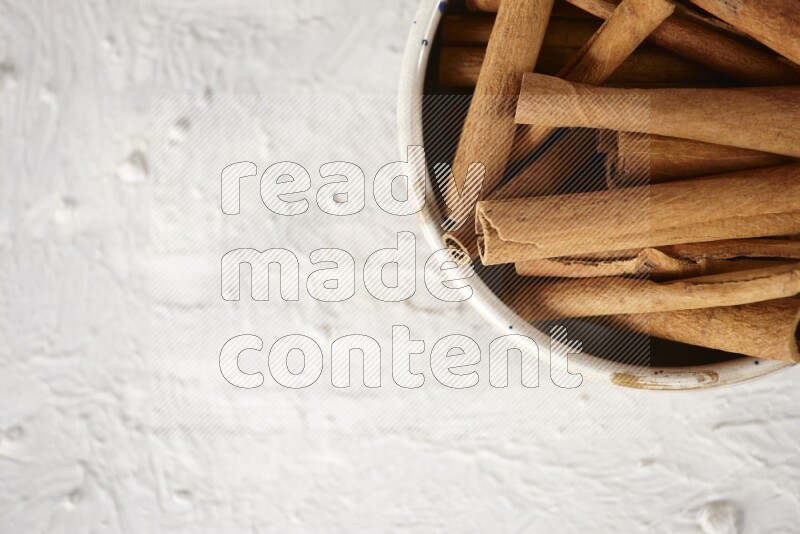 Cinnamon sticks in a ceramic bowl in different angles on white background