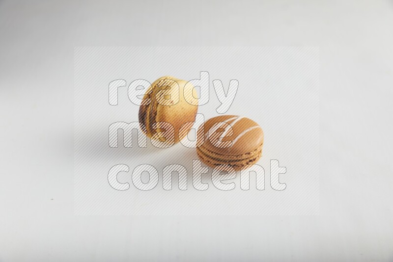 45º Shot of of two assorted Brown Irish Cream, and Yellow Crème Brulée macarons on white background