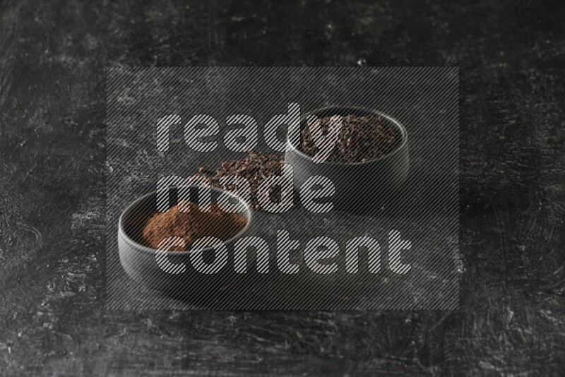 وعاءين من الفخار الأسود أحدهما ممتلئي بحبوب القرنفل والآخر ممتلئ ببودرة القرنفل على خلفية سوداء