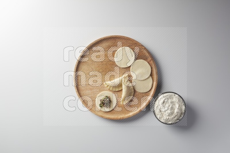 two closed sambosas and one open sambosa filled with meat while flour aside in a wooden dish on a white background