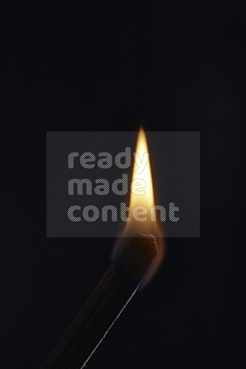 A burning incense stick isolated on dark backdrop