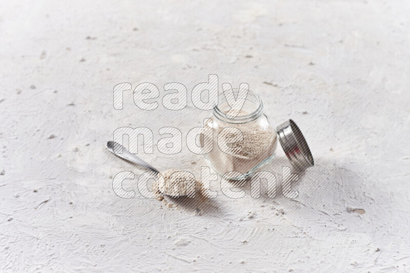 A glass jar full of onion powder on white background