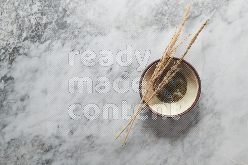 Wheat stalks on decorative pottery plate on grey marble background
