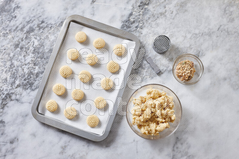 Kahk step by step with its ingredients ghee, sugar, flour, sesame, yeast, water and kahk flavor on grey marble background